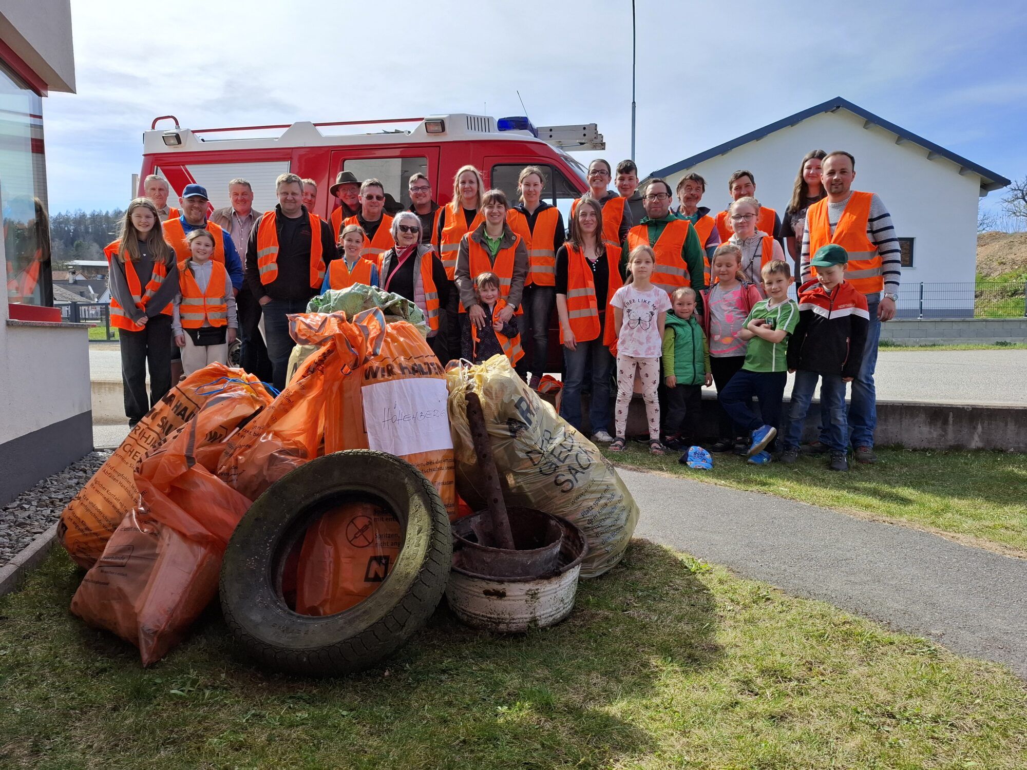 Gruppenbild der HelferInnen und Helfer der Frühjahrsputzaktion der Jägerschaft und Feuerwehr Höhenberg mit dem in der Natur gesammelten Abfall