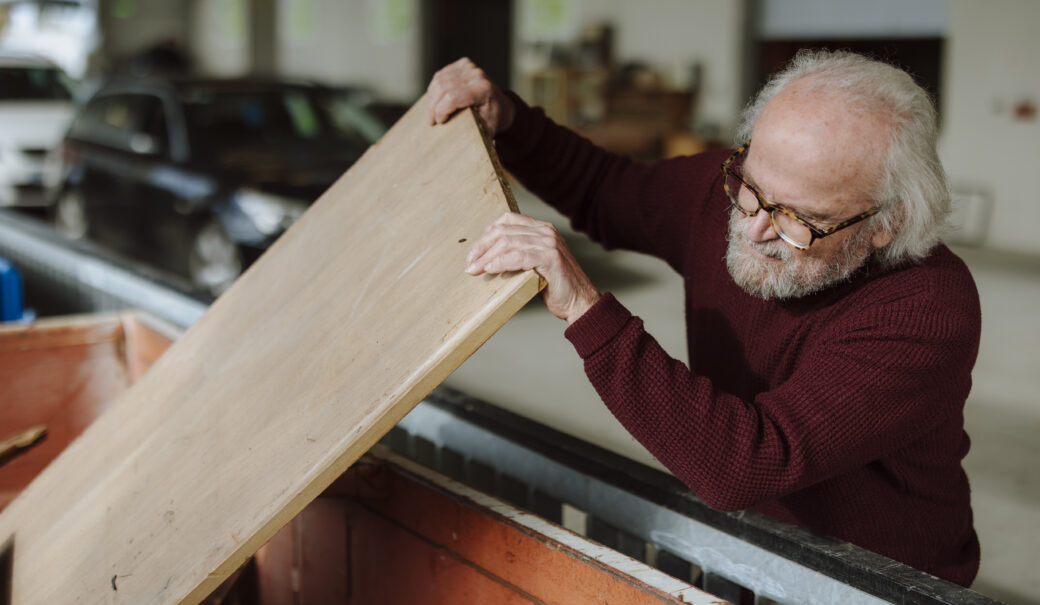 Älterer Herr gibt Holzplatte in WSZ Container.