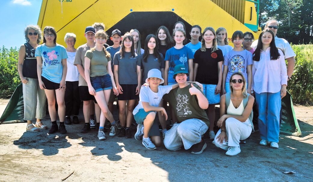 Erwachsene und Kinder vor einem Wender auf der Kompostieranlage